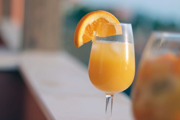 Orange juice in a wine glass with an orange slice.