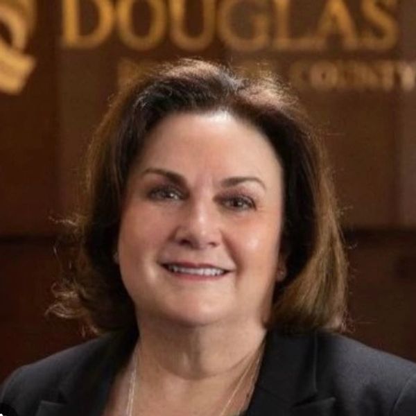 Professional portrait of a smiling woman with brown hair and a dark blazer.