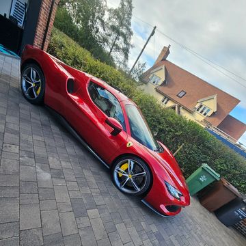 Red Ferrari parked in a driveway beside a house.