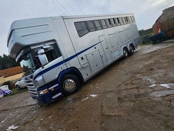 Large silver livestock truck parked on muddy ground.