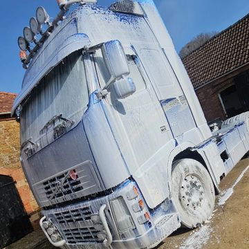 Truck covered in white foam or soap outdoors.