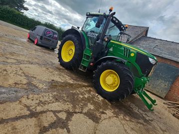 Green John Deere tractor on muddy farm ground.