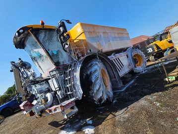 Large construction vehicle being washed outdoors.