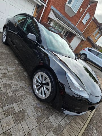 Shiny black Tesla parked on a driveway.