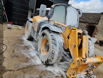 Yellow loader covered in foam on a farm.
