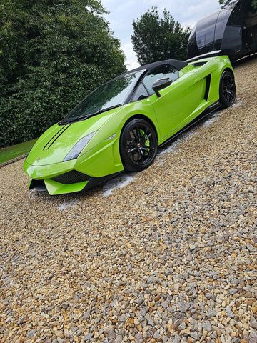 Green Lamborghini sports car parked on gravel.