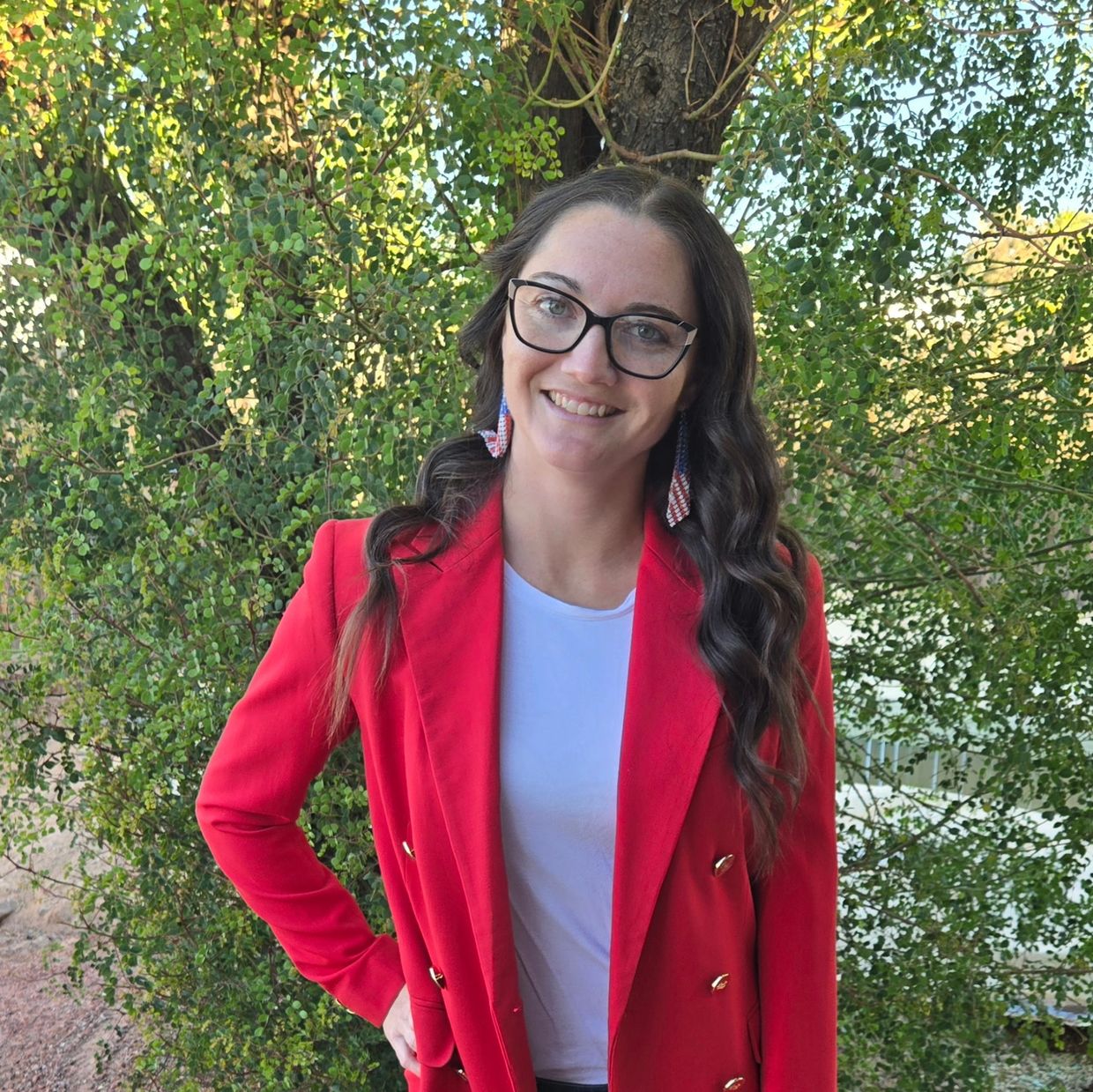 Smiling woman in a red blazer outdoors.