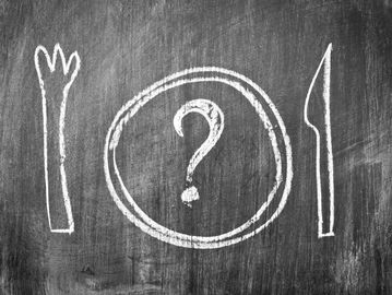 Chalk drawing of a plate with a question mark between a fork and knife on a blackboard.