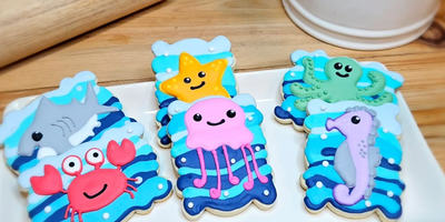 Colorful sea creature cookies with smiling faces on a plate.