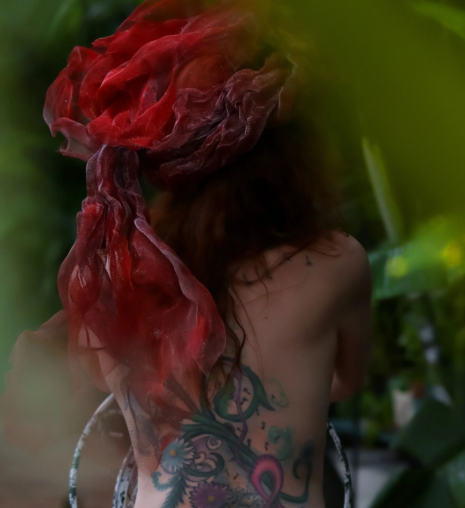 Nude woman seated, with tattoos in a garden