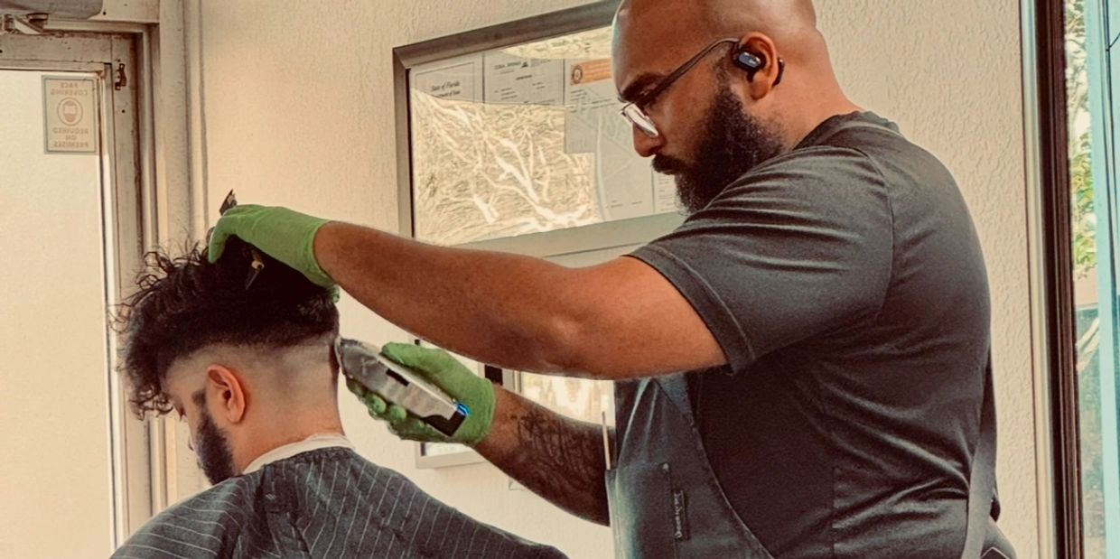 Barber giving a fade haircut to a client in a salon.