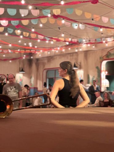 Woman in black dress at a festive indoor event with string lights and decorations.