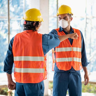 two workers clad in orange high visibility jackets with yellow color helmet