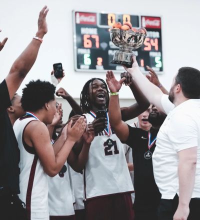 Basketball team celebrates winning with a trophy.