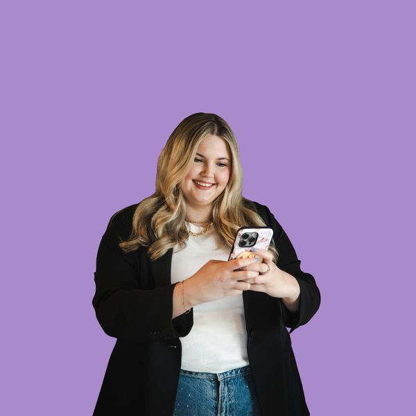 Smiling woman using smartphone against purple background.