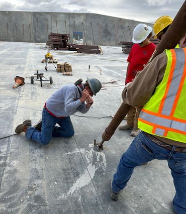 Workers preparing concrete floor with tools.