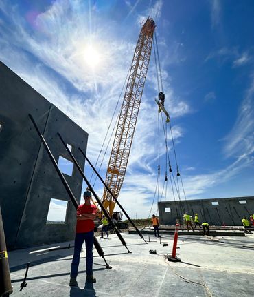 Construction site with crane and workers under blue sky.