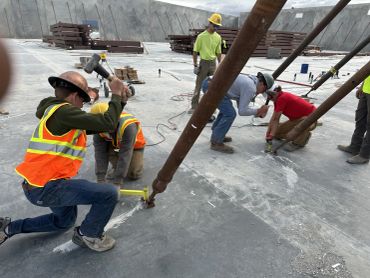 Construction workers installing large pipes on concrete.