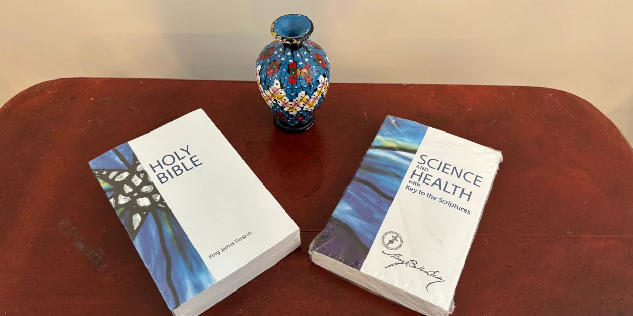 Two religious books and a small decorative vase on a wooden table.