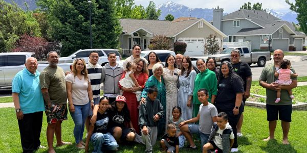 Large family group posing outdoors in a suburban neighborhood on a sunny day.