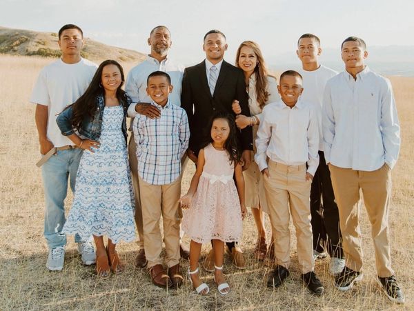 A large family posing outdoors in a sunlit field.
