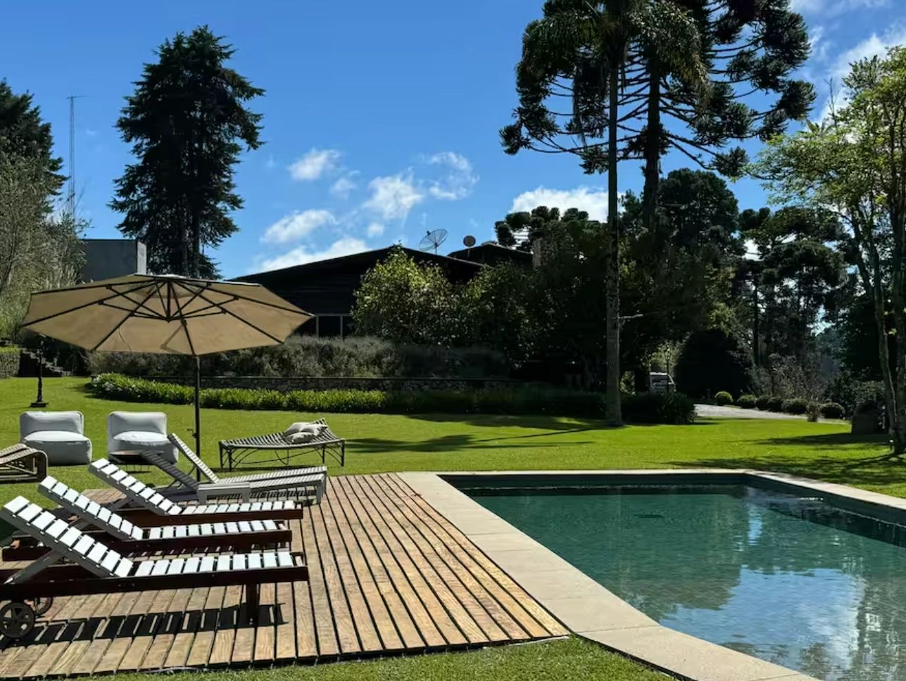 Poolside area with lounge chairs and umbrella on a sunny day.