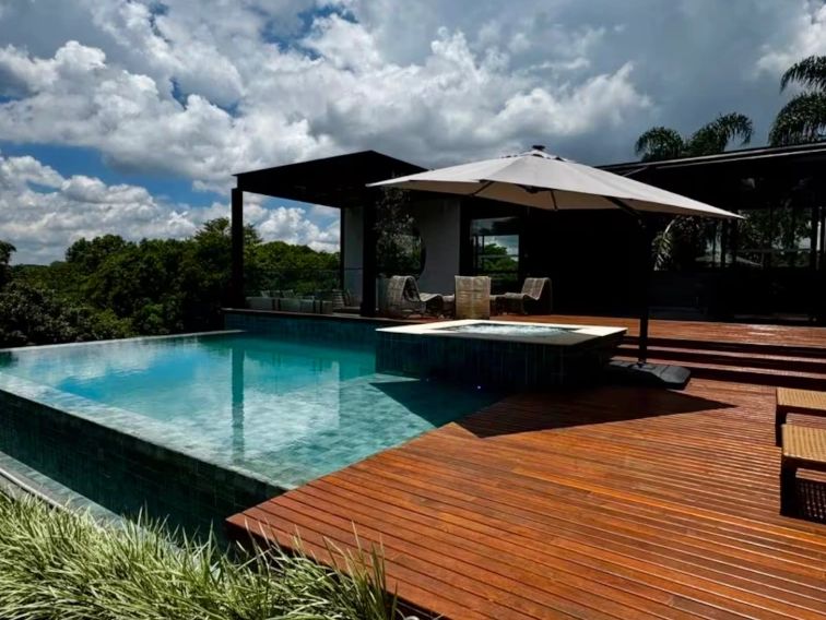 Modern outdoor pool area with wooden deck and umbrella seating.