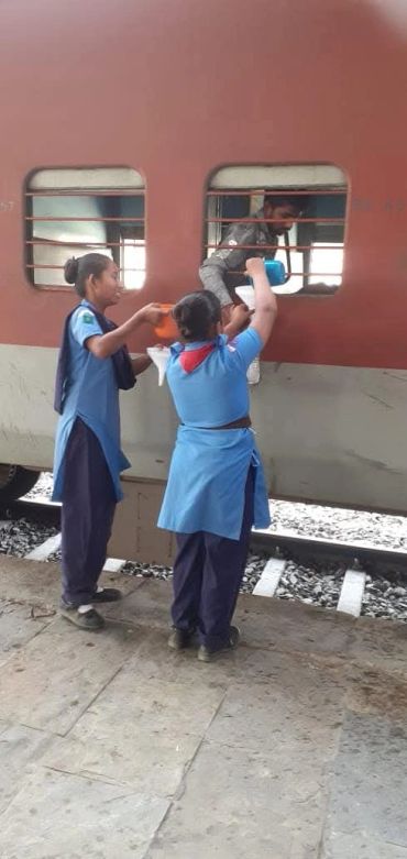 Two women helping a person climb into a train.