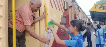 A girl gives water to a man on a train.