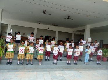 Group of children showing drawings in a school courtyard.
