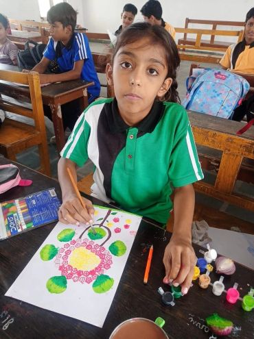 Girl painting a colorful artwork in a classroom.