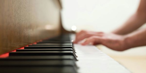 Close-up of hands playing piano keys with soft focus.