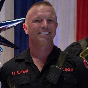 Smiling firefighter captain in uniform with name S.F. Runyan.
