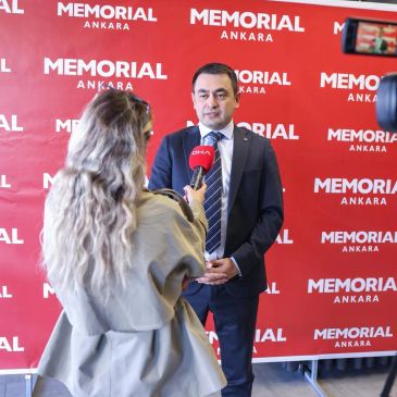 Hastane önünde röportaj veren adam ve mikrofon tutan kadın.