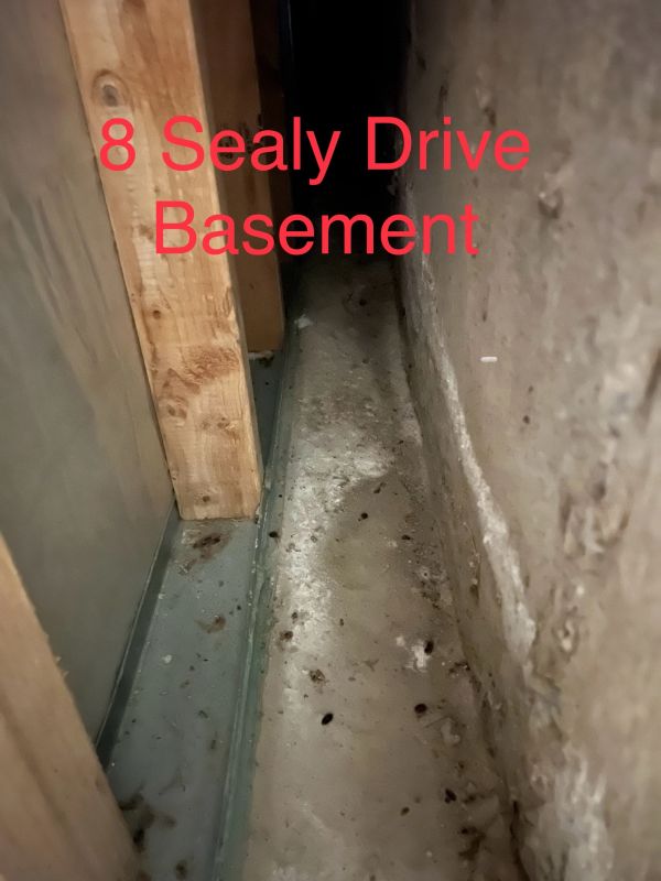 Narrow basement corner with concrete floor and wooden beam.