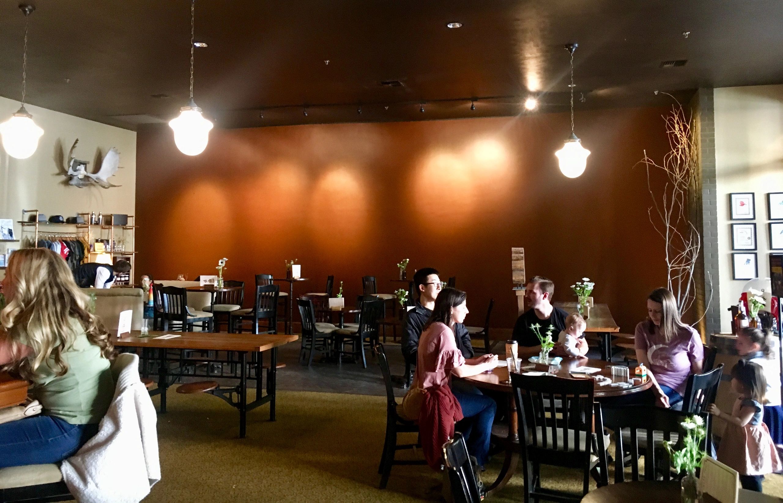 Red painted wall behind tables and chair with patrons in Montgomery Distillery 