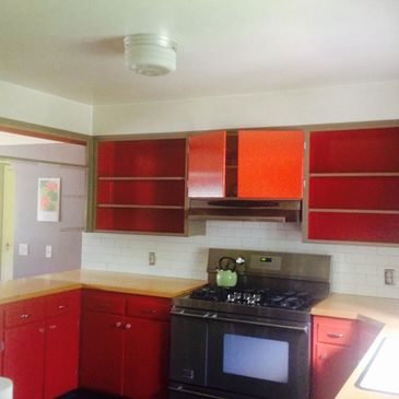 Completed re-done kitchen cabinets with red paint on insides of shelves and outer doors