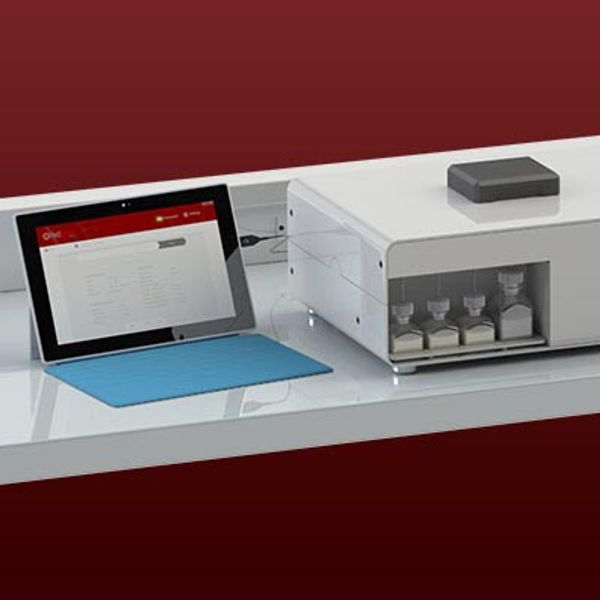 Tablet connected to a modern laboratory instrument on a white table.