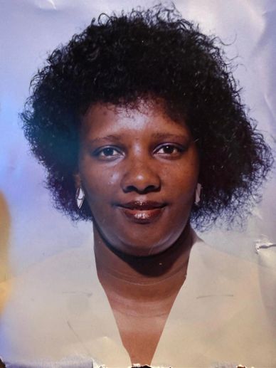 Portrait of a woman with curly hair and earrings against a blue background.