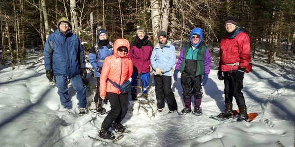 Northern Paddle Trail club members in a group photo with snowshoes on in the forest.