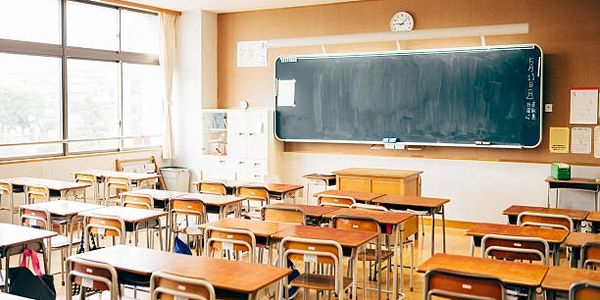 Empty classroom with wooden desks and a large blackboard.
