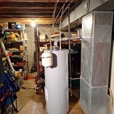 Basement with water heater and ductwork near shelves storing various items.