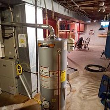 Water heater installed in a basement with exposed ceiling and concrete floor.