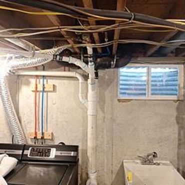 Laundry room with washer, dryer, plumbing, and ventilation pipes.