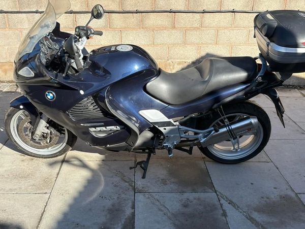 A black BMW motorcycle parked on tiled pavement.