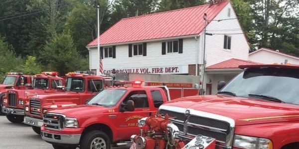 Red fire trucks lined up at a volunteer fire department building.