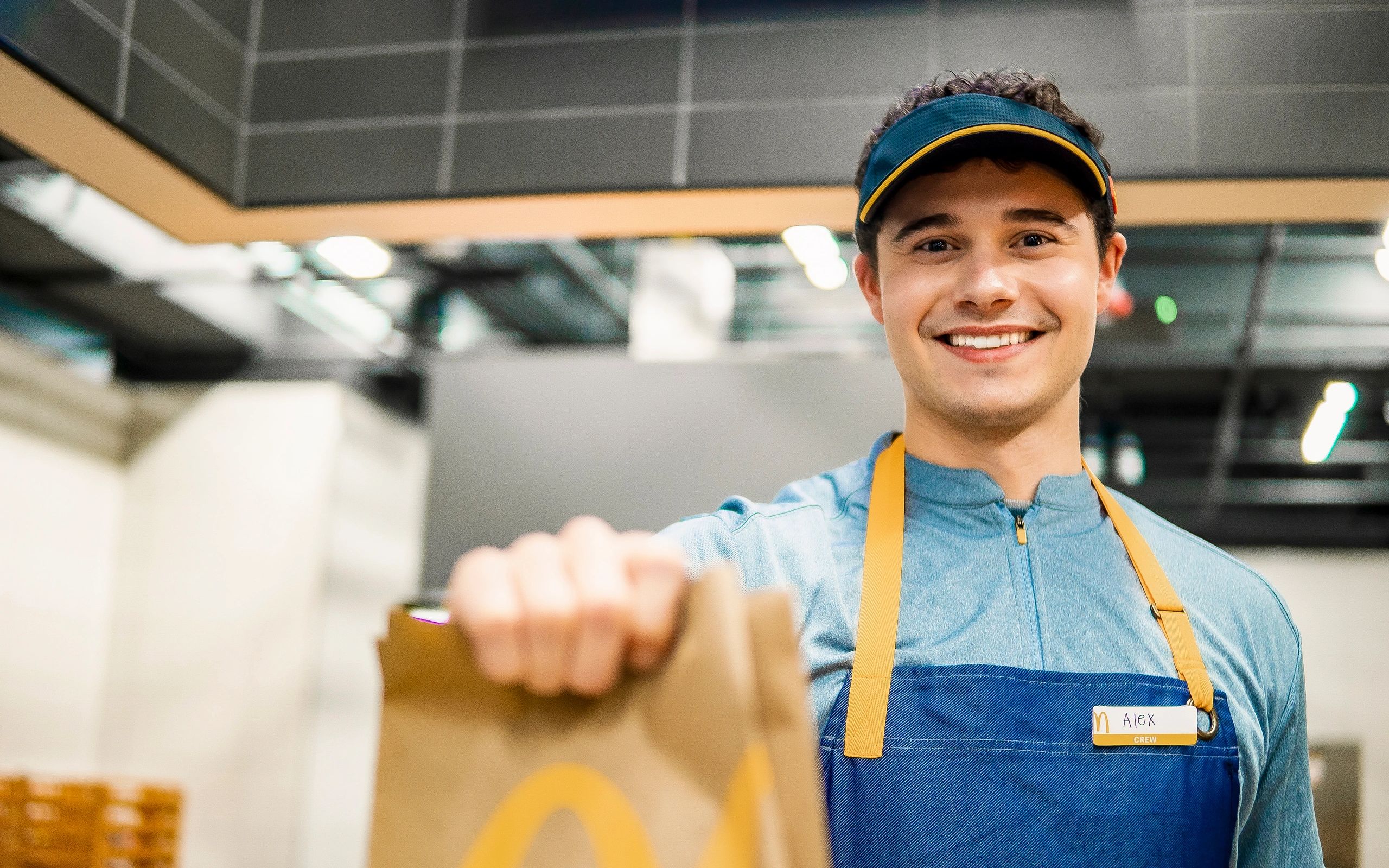 Smiling McDonald's employee handing over a bag.