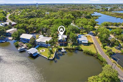 Aerial view of waterfront houses surrounded by greenery and water bodies.