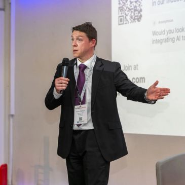 Man in a suit giving a presentation with a microphone.