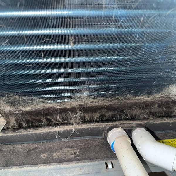 Dirty AC evaporator coil with heavy dust buildup reducing airflow and cooling efficiency.